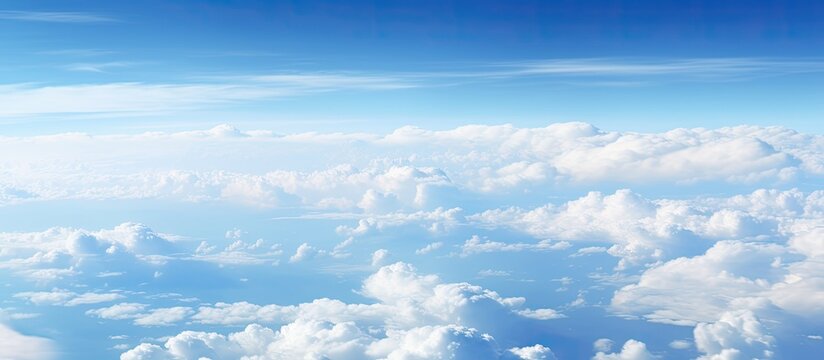 Fototapeta A captivating aerial perspective of fluffy clouds against a blue sky above the ocean seen from an airplane window with copy space image