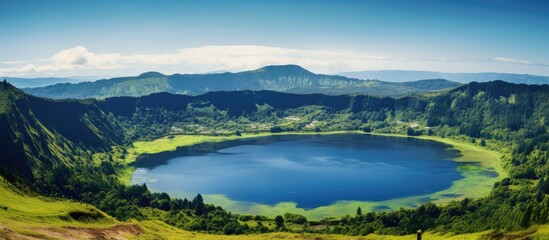 Obraz premium Summer scenery of a volcanic crater lake with a clear blue sky and lush green surroundings ideal for a copy space image