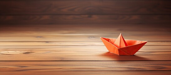 An adorable origami paper boat displayed on a wooden surface with a clear copy space image available