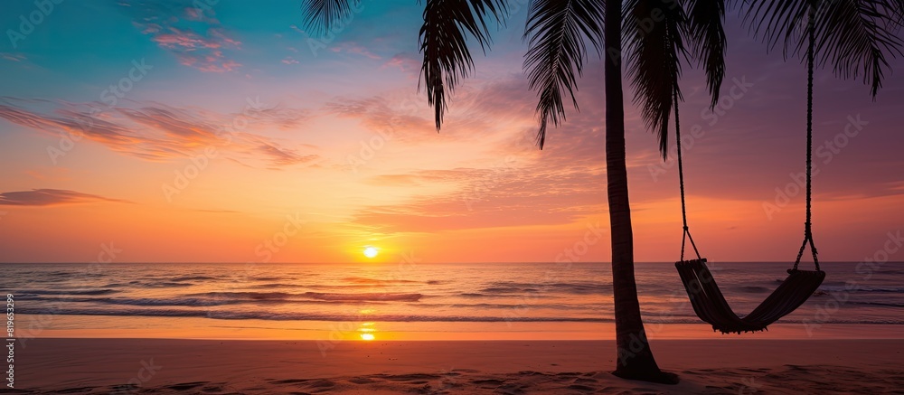 Poster a swing is attached to a palm tree on a sandy tropical beach by the ocean during sunset creating a t