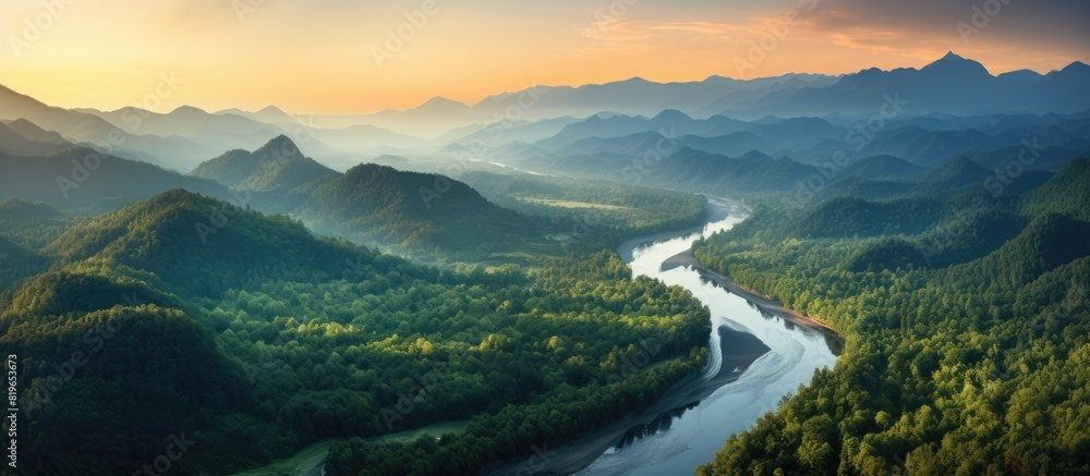 Poster aerial view of a mountain range and tall forest by a river during a summer evening with orange horiz