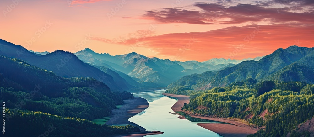 Poster aerial view of a mountain range and tall forest by a river during a summer evening with orange horiz