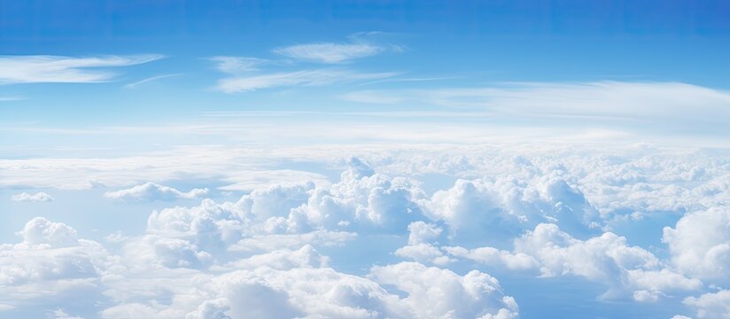 Fototapeta A captivating aerial perspective of fluffy clouds against a blue sky above the ocean seen from an airplane window with copy space image