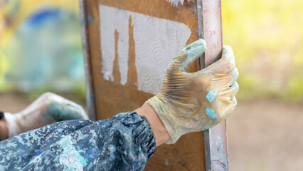 Focused hands clad in gloves apply a stencil to a screen, ready to print an image onto fabric. The...