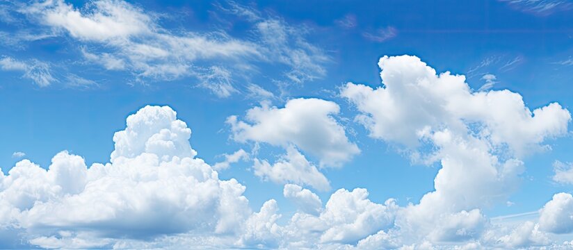 Summer daytime panoramic view of a bright and clear blue sky with fluffy clouds creating an abstract wallpaper background representing the beauty of outdoor nature with copy space image
