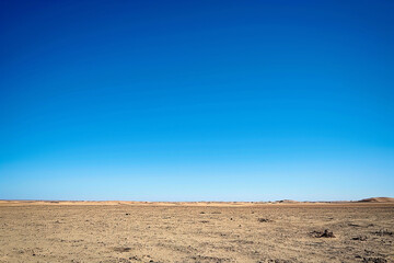 landscape in the empty desert with a clear blue sky, vast expanse, wide lens shot, photorealistic // ai-generated 