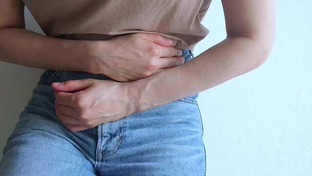 Woman suffering from stomach ache, holding belly, abdominal or menstrual pain.