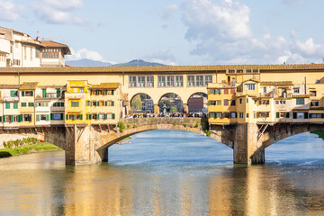 Obraz premium Florence, Italy - April 10, 2024: View of the Vecchio Bridge in Florence with tourists crowding its surroundings in Florence, Italy