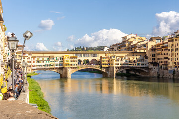 Obraz premium Florence, Italy - April 10, 2024: View of the Vecchio Bridge in Florence with tourists crowding its surroundings in Florence, Italy