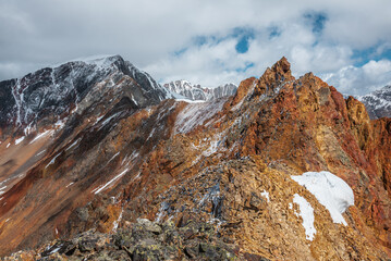 Vivid sharp pinnacle in sunlight. Shiny pointy peak of gold color. Colorful red rocky peaked top....