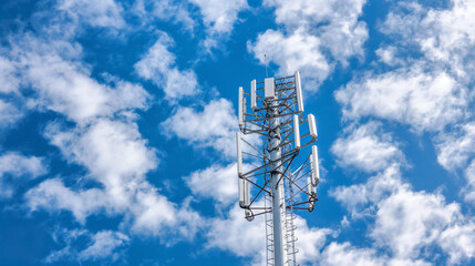 Communications cell tower mobile phone data blue sky clouds.