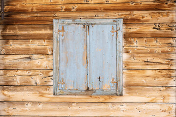 Closed wooden window with old green paint on wooden cabin
