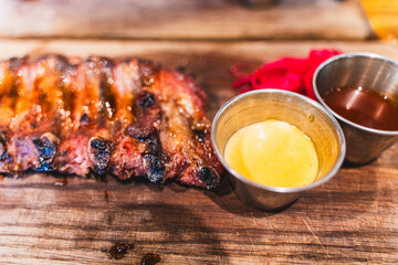 Grilled pork ribs with mustard and tomato sauce on a wooden plank. Selected focus