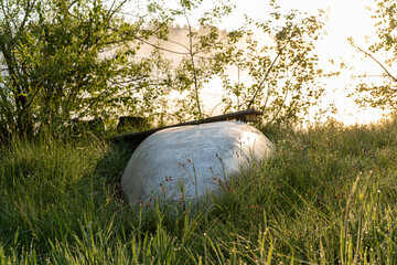 Morning light over lake with flipped canoe in grass with dew