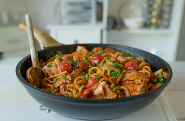 Pan fried salmon with creamy tomato sauce an spaghetti in a skillet