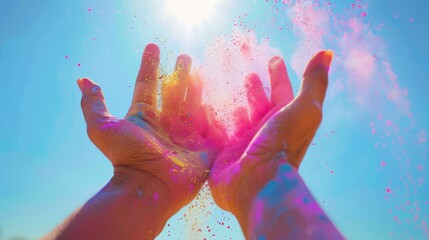 Close-up of hands holding handfuls of colorful powder, ready to be thrown into the air against a backdrop of radiant sunshine.