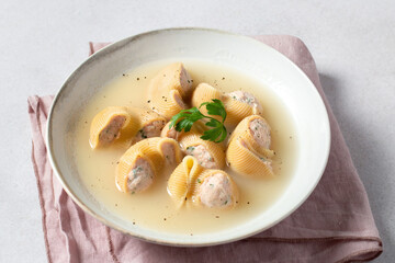 Traditional Catalan Christmas dish Escudella in white plate on table, stuffed pasta in meat broth, top view
