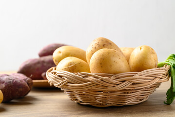 Raw potatoes and purple sweet potatoes on wooden table with white background, Food ingredient
