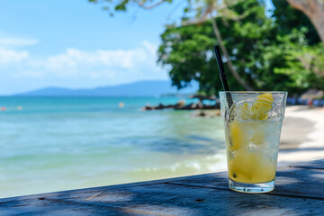 landscape with a glass of lemon juice with ice and a straw on a beautiful beach, sunshine, sea view, mountains in background, photorealistic // ai-generated 