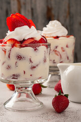 Strawberries with cream in a glass cup on cement table. Copy space.