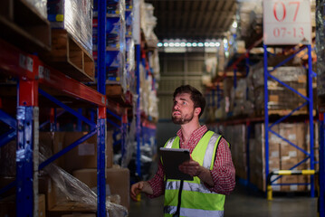 Smart caucasian man warehouse worker wearing safety vests checking inventory stock online...