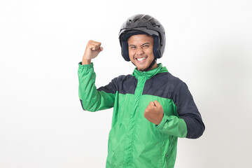 Portrait of Asian online taxi driver wearing green jacket and helmet raising his fist, celebrating success. Isolated image on white background
