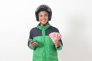 Portrait of Asian online taxi driver wearing green standing against white background, smiling and...