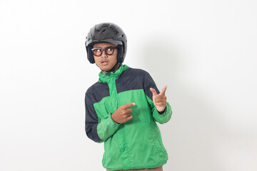Portrait of funny Asian online taxi driver wearing green jacket and helmet pointing at empty space with finger. Isolated image on white background