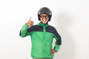 Portrait of funny Asian online taxi driver wearing green jacket and helmet showing thumb up hand gesture. Isolated image on white background