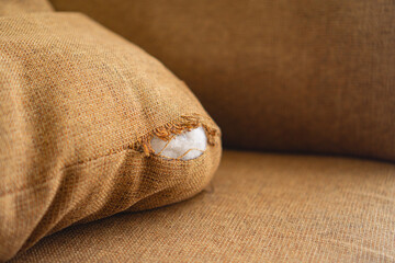 A brown torn sofa cushion made from linen, with an interior made from polyester fiber