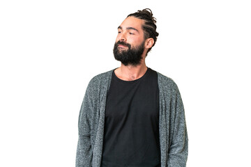 Young man with beard over isolated chroma key background having doubts while looking side