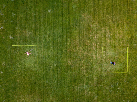 Speedminton being played by two players on a grassy pitch outdoors - racket sport which is a cobination of tennis, badminton and squash
