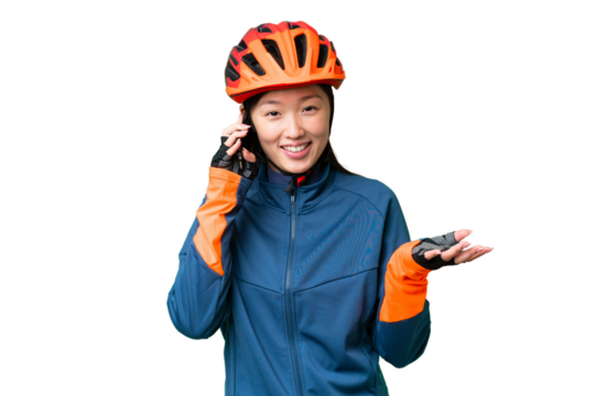 Young cyclist woman over isolated chroma key background keeping a conversation with the mobile phone with someone