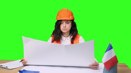 Female engineer with safety helmet looking at blueprint on the chroma key