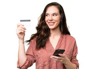 Young caucasian woman over isolated background buying with the mobile with a credit card while...
