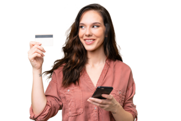 Young caucasian woman over isolated background buying with the mobile with a credit card while thinking