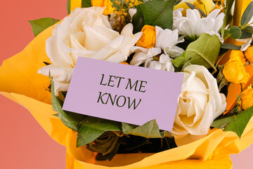 Information Concept. LET ME KNOW written on a purple business card in a bouquet of delicate roses