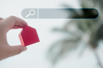 Man holding red wood home and show search bar. Concept of a website to find real estate on the...