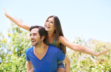 Obraz premium Couple, piggy back and nature together for relationship, bonding love and care in outside date for romance. Blue sky, trees and summer holiday with airplane game, travel and adventure in sunshine