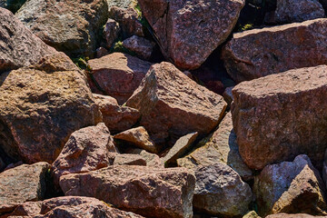 Pile of red pink granite rock stones, boulders in sunlight.Lumps