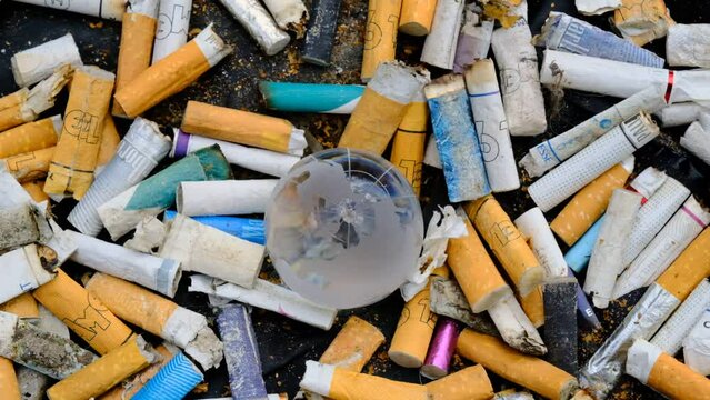 Human health concept. A lot of cigarette butts surrounded a crystal globe