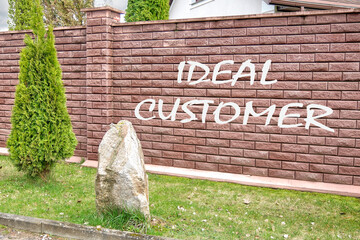 Business ideal customer concept. Copy space. Ideal customer symbol writing on a red brick fence