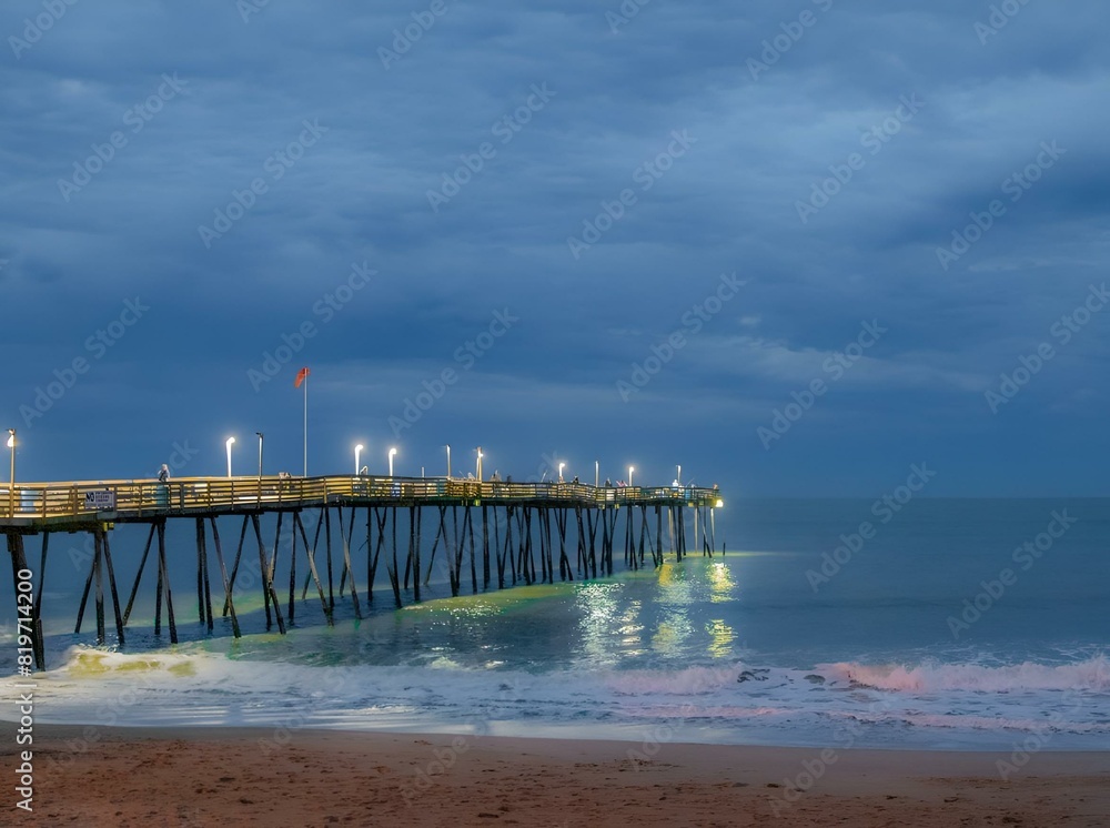 Wall mural Fishing pier in the Outer Banks of North Carolina with surf on a cloudy evening