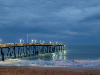 Fishing pier in the Outer Banks of North Carolina with surf on a cloudy evening