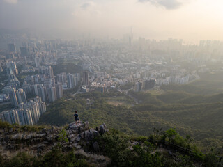 view from peak of large city towards green hills and hazy sky