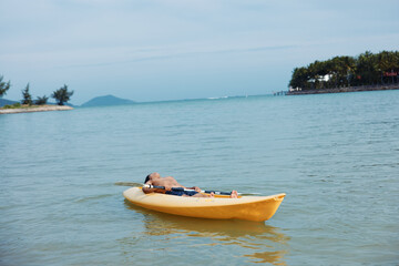 Active Vacation: Asian Man Enjoying Kayaking Adventure on Tropical Beach