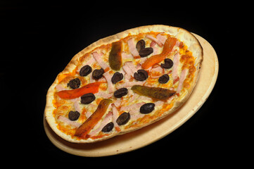 Pizza with ham, tomato and olives on a black background