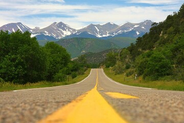 a street with yellow line on the side and mountains in the distance