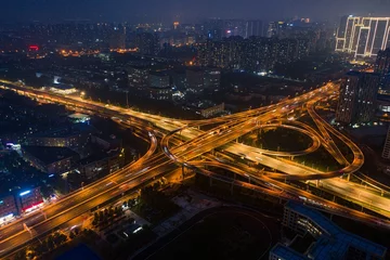 Fototapeten Aerial view of an intersection illuminated by orange-yellow street lights at night. © Wirestock