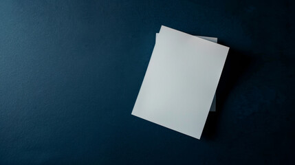 Minimalist composition featuring two blank white papers on a deep blue background.